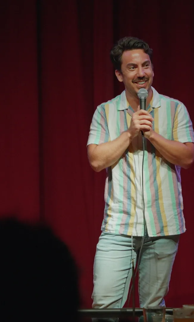 Evan Lopez on stage in front of a red curtain